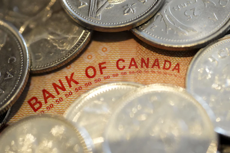 The words 'Bank of Canada' on a bank note is seen in the midst of a pile of coins