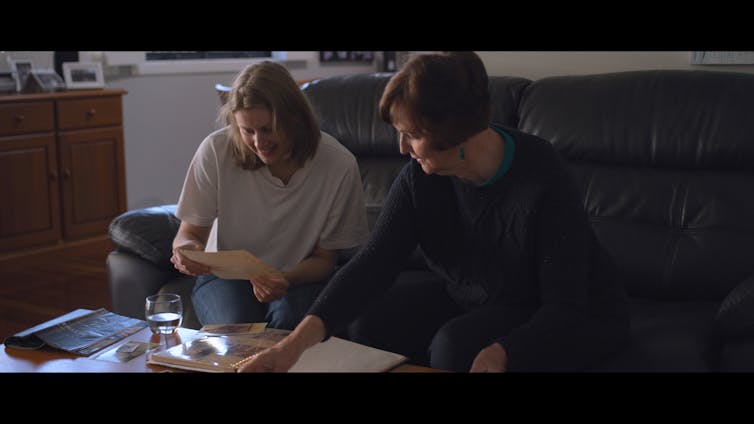 Kathryn Joy and a woman look at photographs.