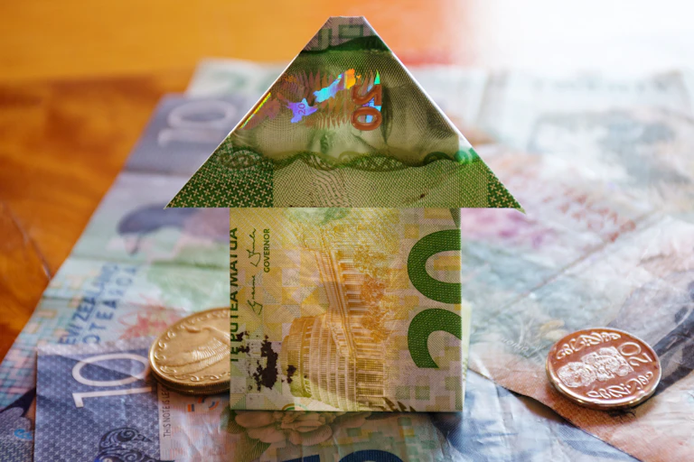 House folded from money with New Zealand dollar notes in background