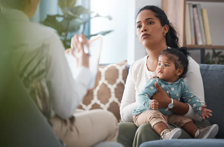 A mother sits with a toddler on her lap.
