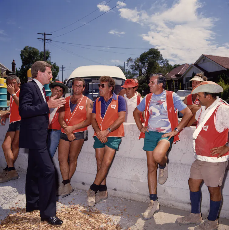 Politician in a suit (Laurie Brereton) posing with tanned road workers wearing orange vests
