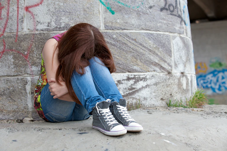 Une adolescente recroquevillée assise sur le sol