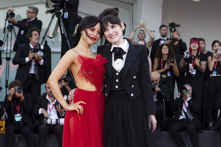 Jenna Ortega in a red dress and Winona Ryder in a black tuxedo dress.