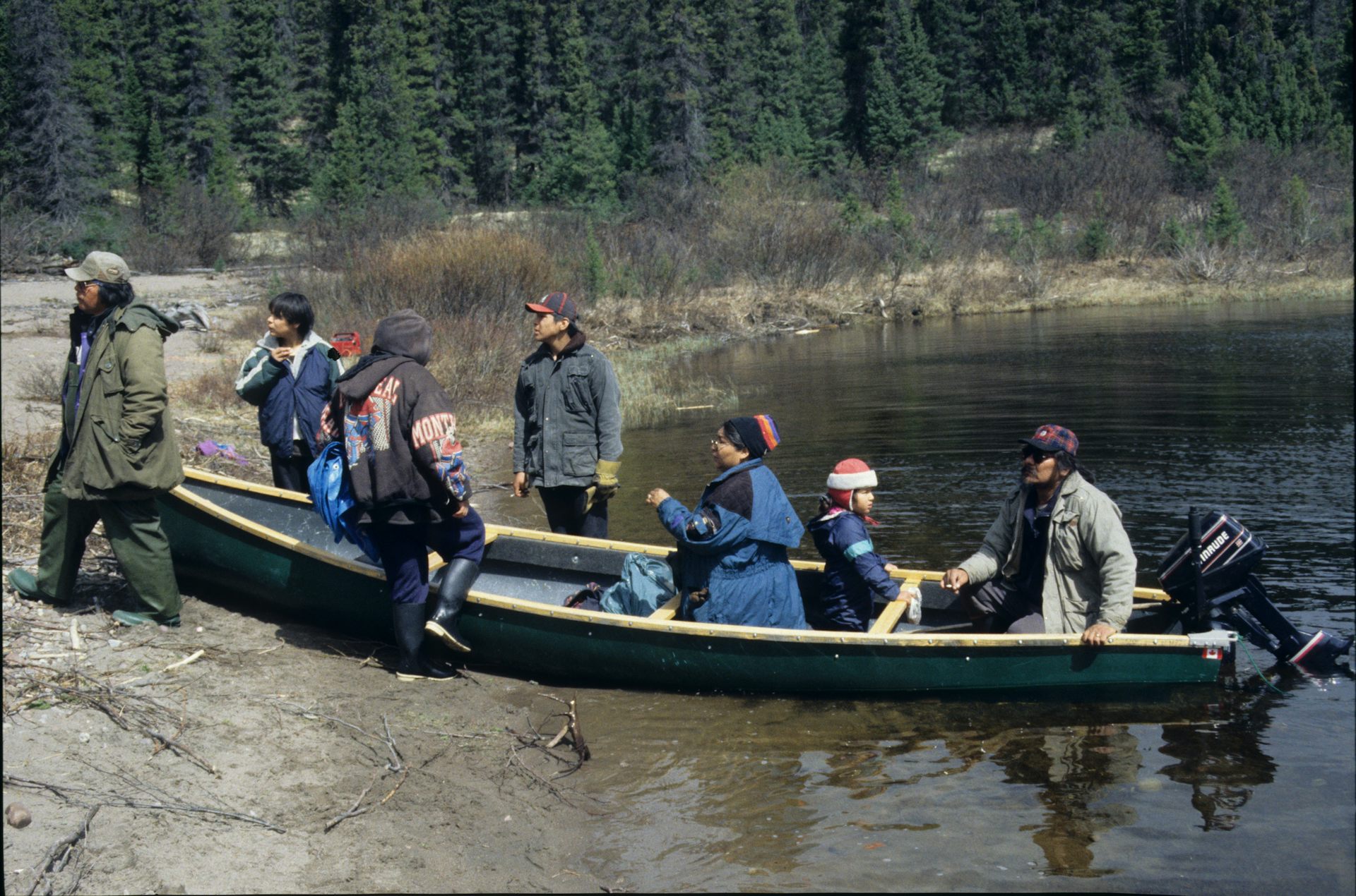 Multiple generations of an Innu family disembark from a motorised canoe.