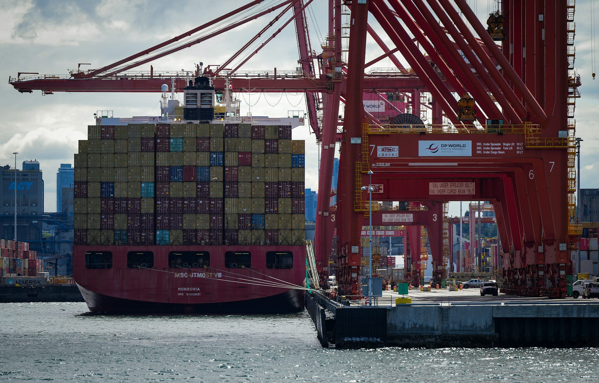 A cargo container ship is pictured at port from the stern.