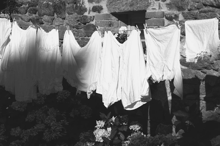 black and white image of white vintage underwear hanging to dry on line, brick wall in background