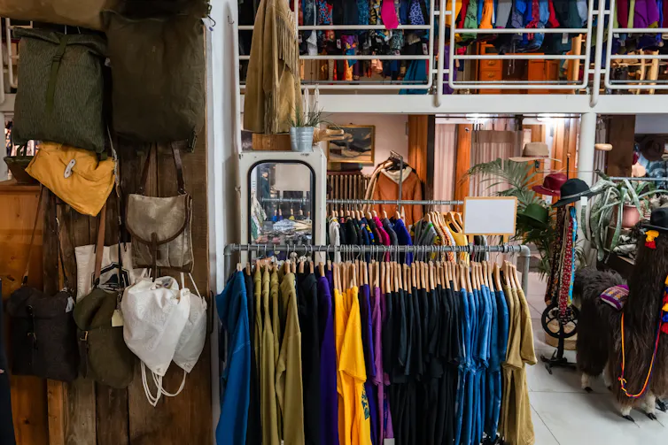 rails of colourful secondhand clothes in charity shop, hats, coats etc