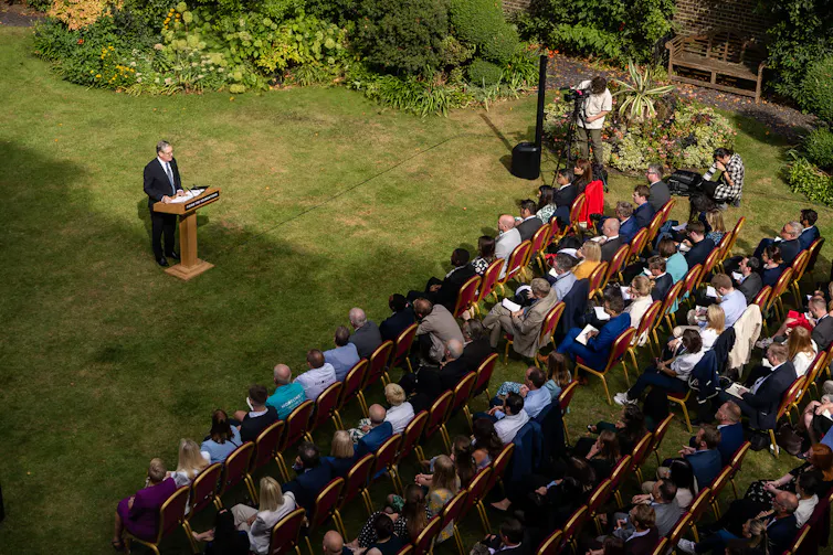 Keir Starmer giving a speech in a garden in front of an audience.
