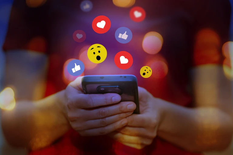 Une personne avec un smartphone et des émojis.