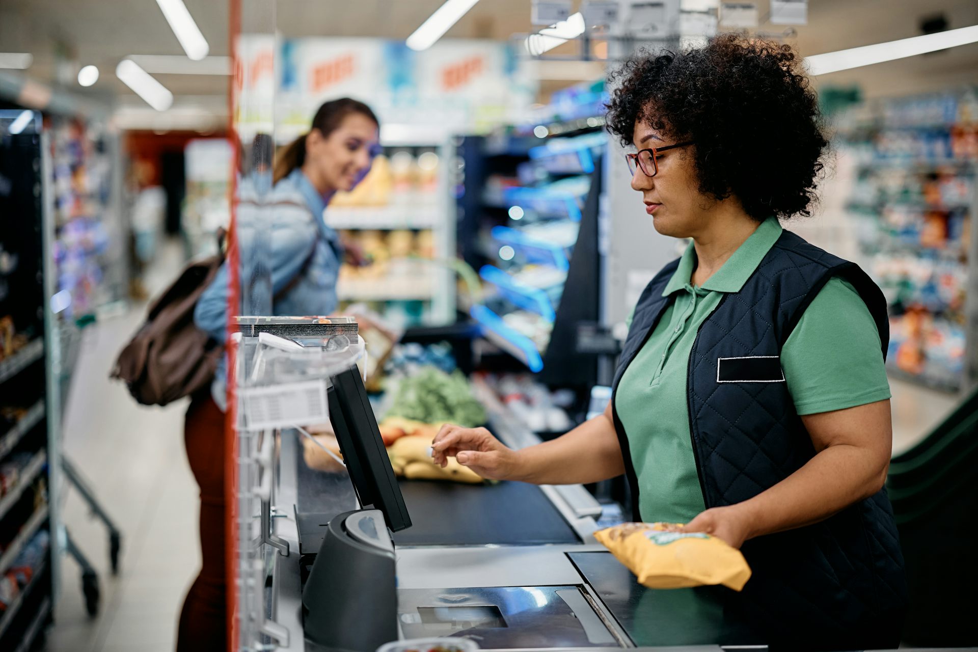 Une femme scanne des produits dans une caisse de supermarché