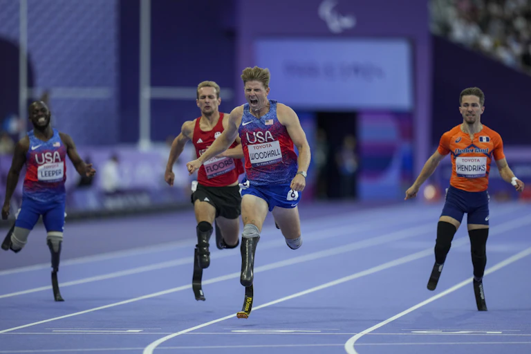 Four men running on a track using running blades