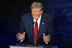 A grimacing man gestures with his hands like he's playing an accordion.