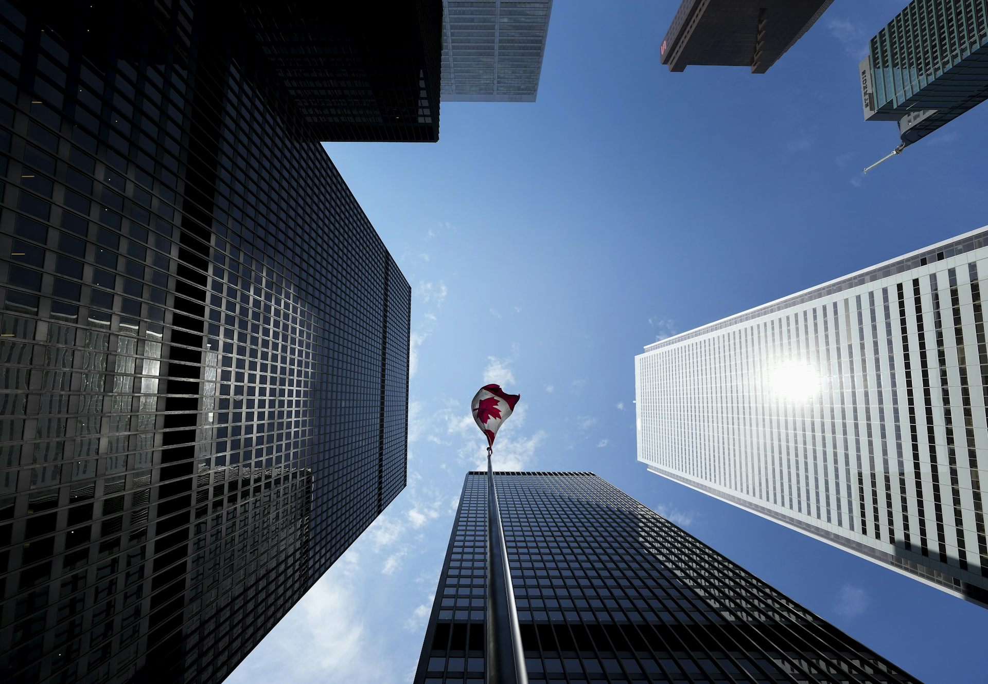 Upward shot of a Canadian flag surrounded by tall buildings