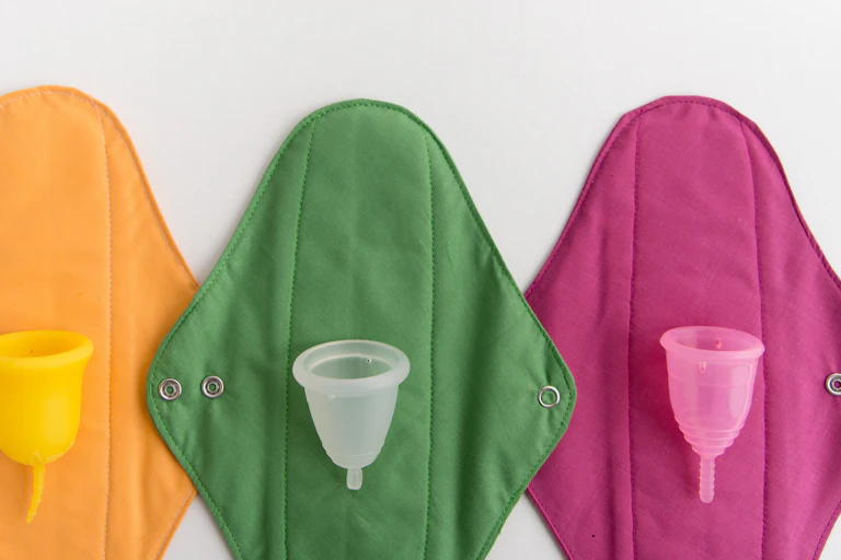 A row of cloth pads with reusable menstrual cups.