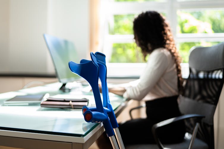 A woman in an office with crutches leaning against her desk
