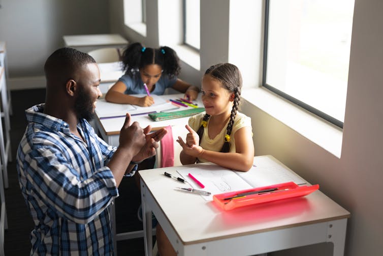 A teacher communicating with a primary school student in sign language