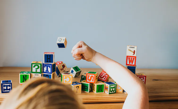 Child knocking down alphabet blocks.