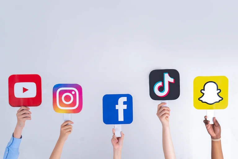 Children's hands hold up signs of social media icons, including Instagram, TikTok and Snapchat.