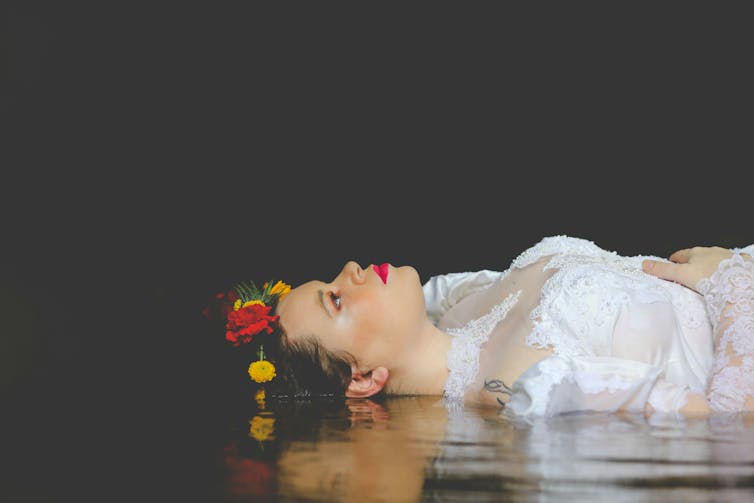A woman in costume lies on a stage.
