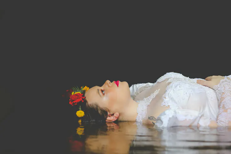 A woman in costume lies on a stage.
