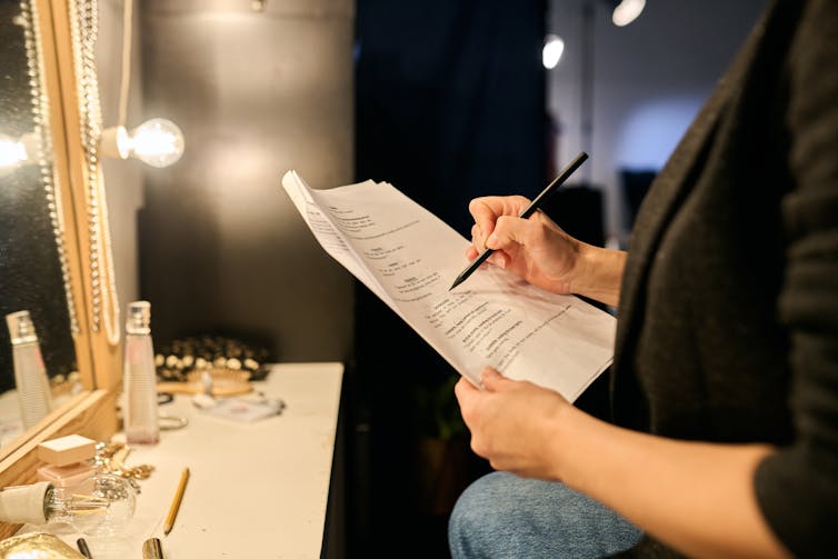 A woman writes on a script.