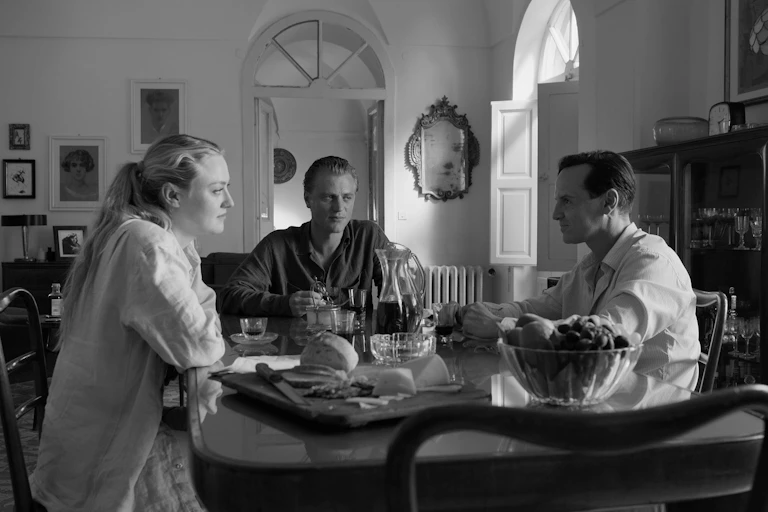 Dos hombres y una mujer hablan alrededor de una mesa.