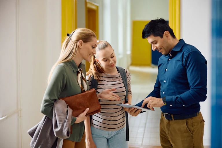 Mother and teenager daughter looking at tablet with teacher