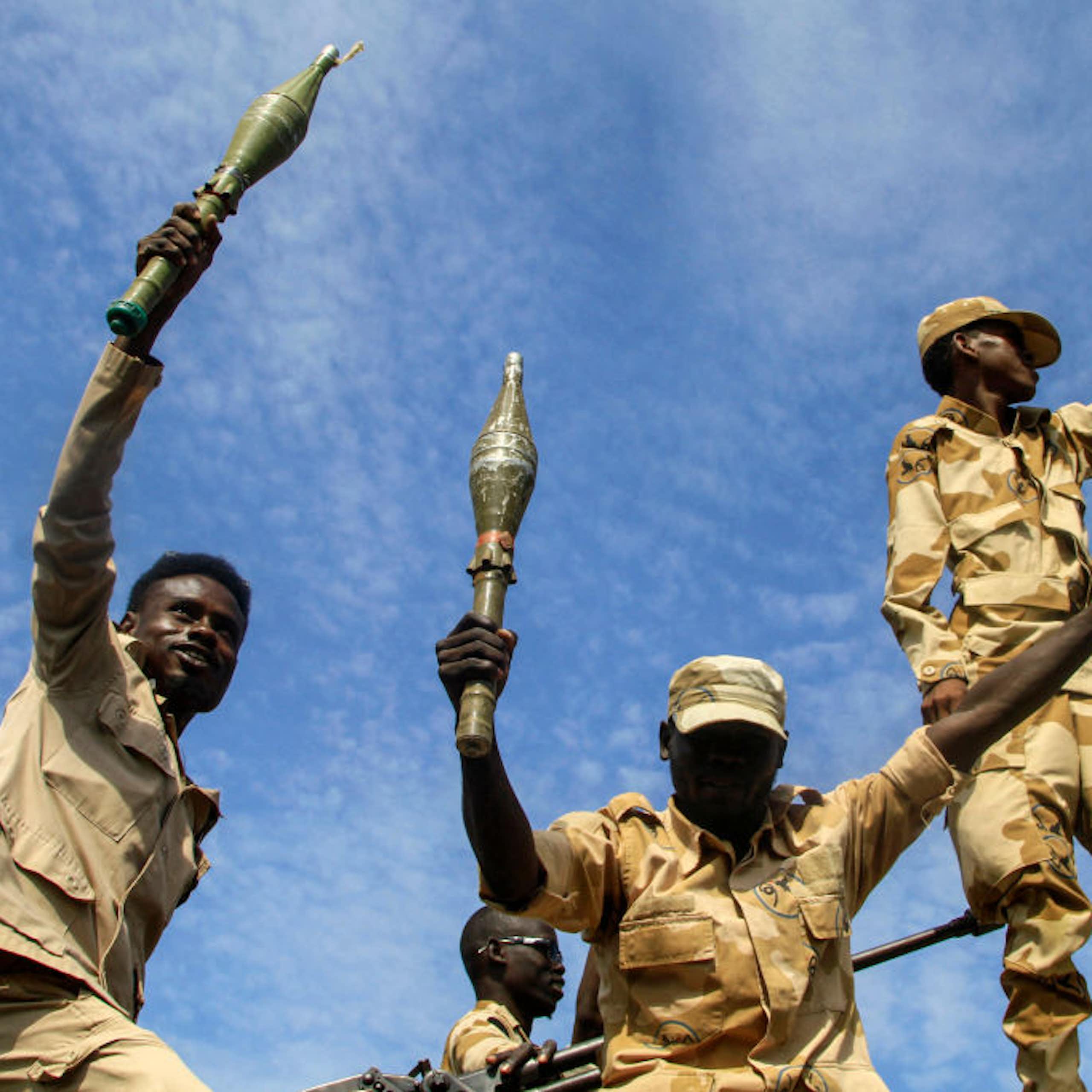 Two men holding hand grenades while another holds up a clenched fist