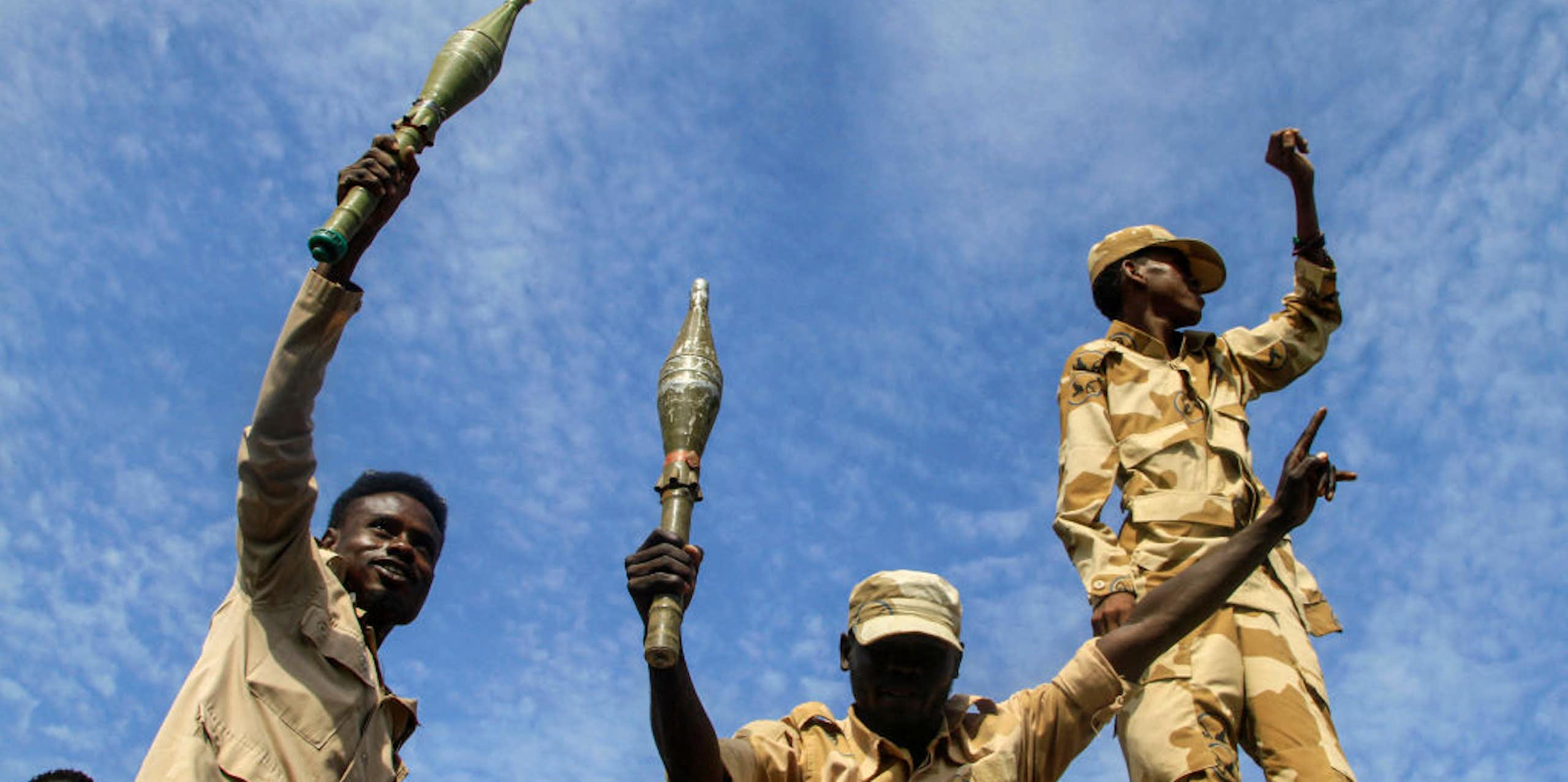 Two men holding hand grenades while another holds up a clenched fist
