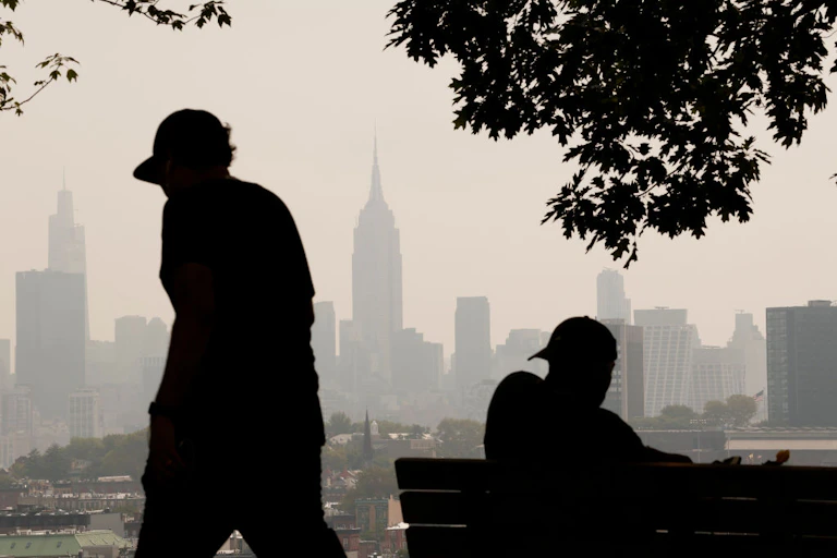 Silhouette of two people against a hazy city skyline