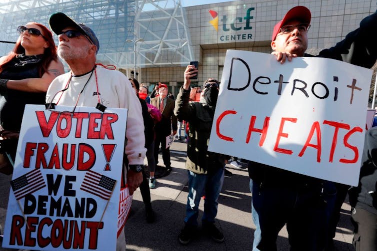 Protesters with 'Detroit Cheats' and 'Voter Fraud' signs