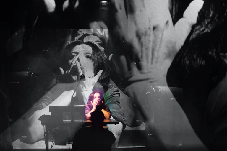 A woman on stage with images of her repeated in black and white in the background