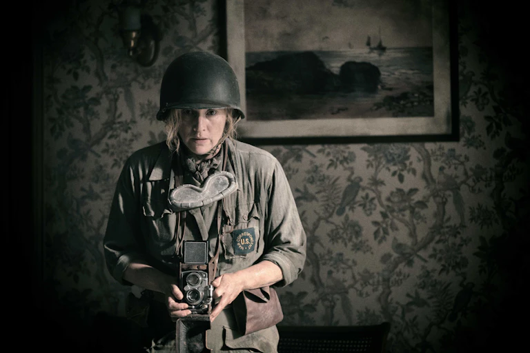 A woman dressed in army fatigues with an old-fashioned camera.