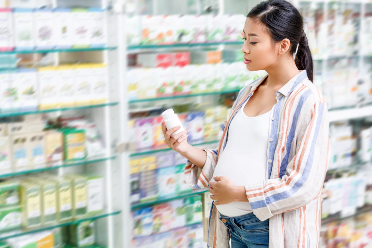 A pregnant woman looks at medications in a pharmacy.