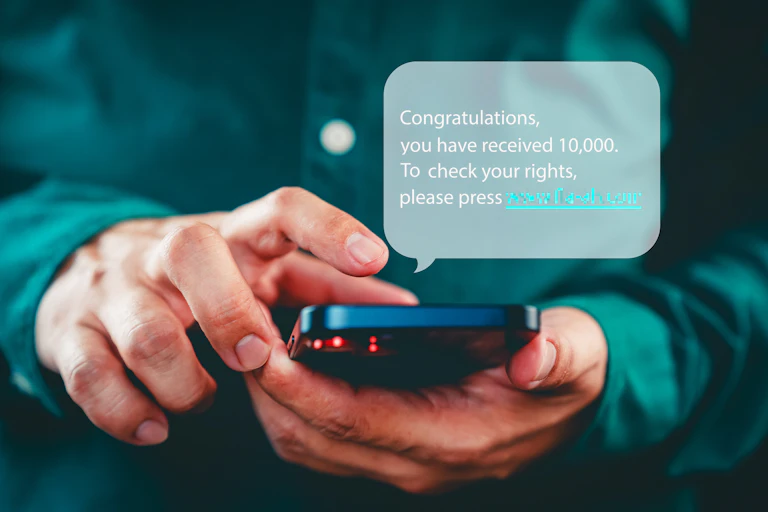 Close-up of a man's hands holding a phone with a pop-up message with scam text in it.