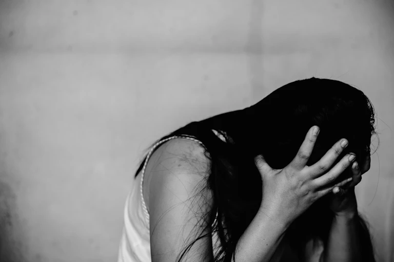 A black and white photo of a distresses woman with her head in her hands