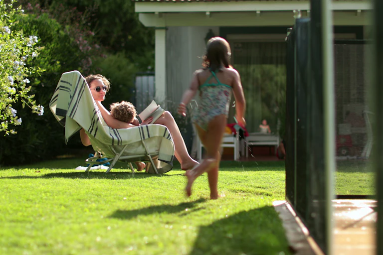 Woman and two children beside a backyard swimming pool