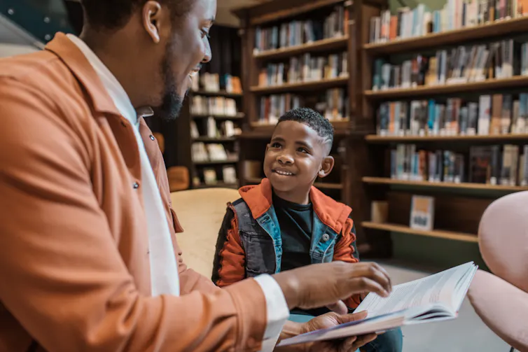 A man reads with a boy in a library.