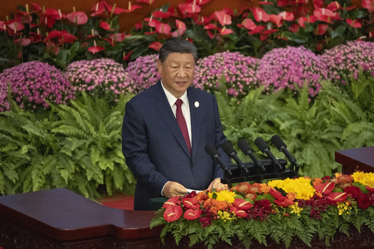 Xi Jinping surrounded by flowers as he delivers a speech.
