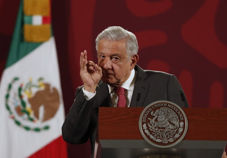 Andres Manuel Lopez Obrador speaks during a press conference in front of a Mexico flag.