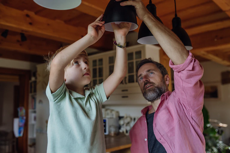 A child and parent screw in a lightbulb.
