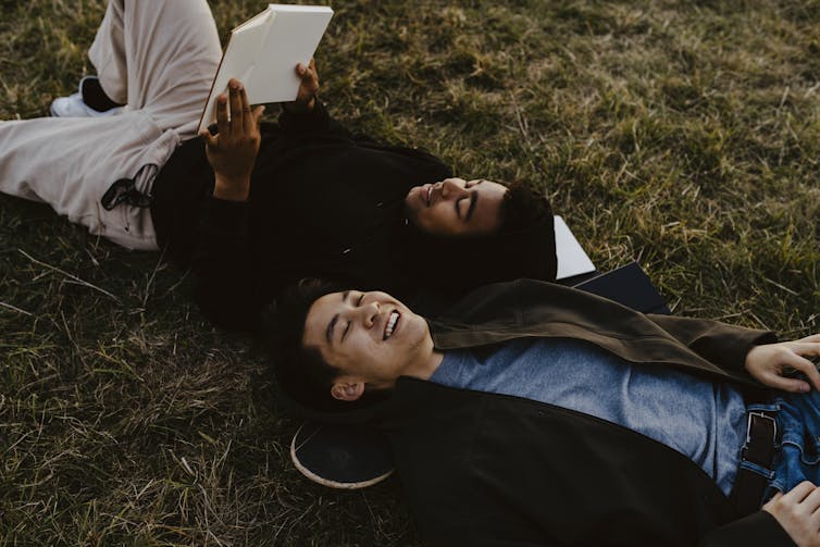 two young men lying on the grass looking at the sky