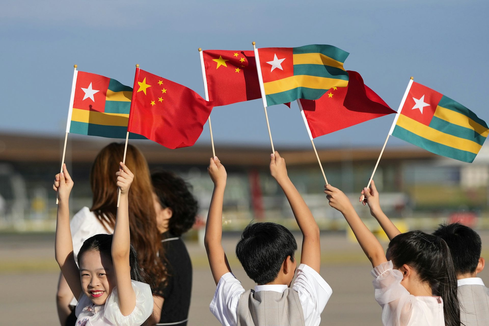 Chinese children waving the national flags of Togo and China.