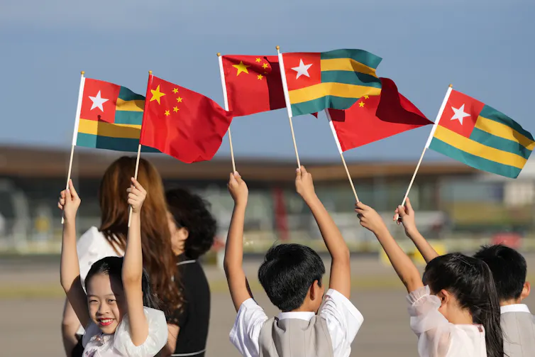 Chinese children waving the national flags of Togo and China.