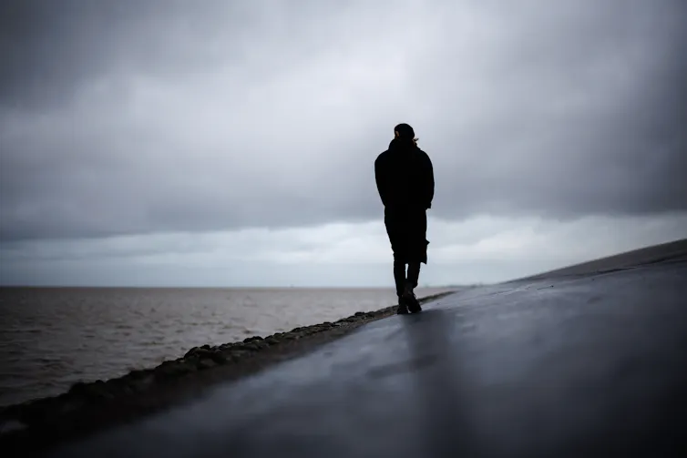 Man walks alone along beach.
