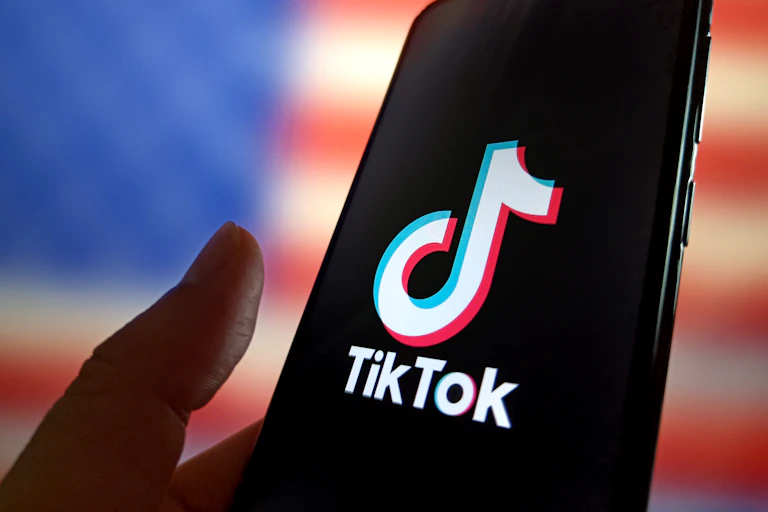A hand holds a phone with the tiktok logo displayed.