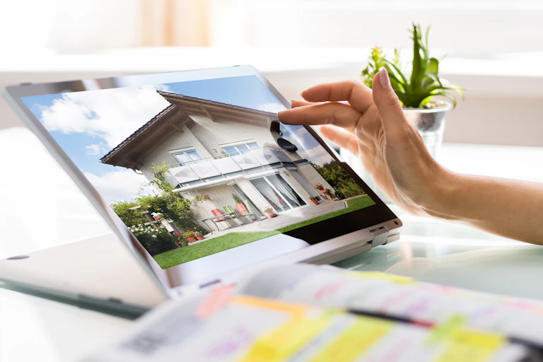 Person viewing picture of a house for sale on a laptop