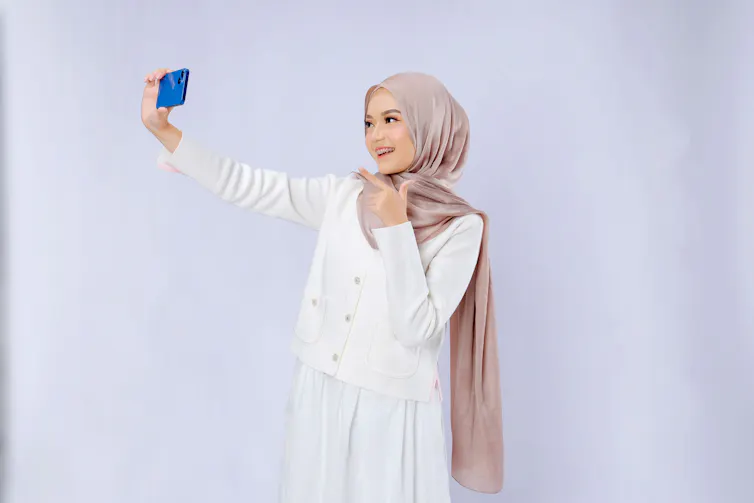 A woman in a hijab takes a selfie.