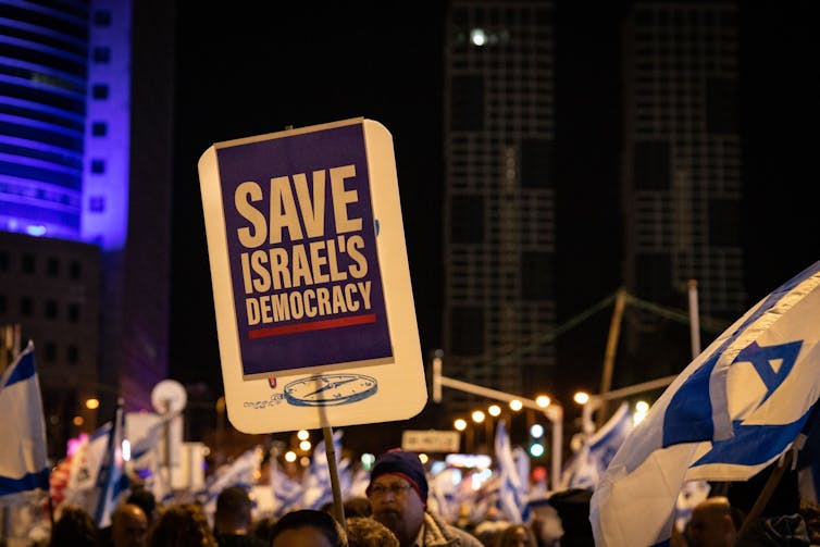 Demonstrators in Israel holding a placard reading 'save Israel's democracy'.