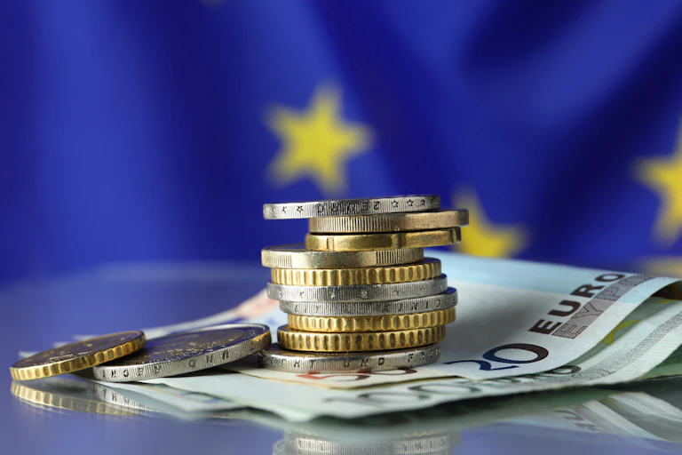 EU flag with euro coins and notes in the foreground